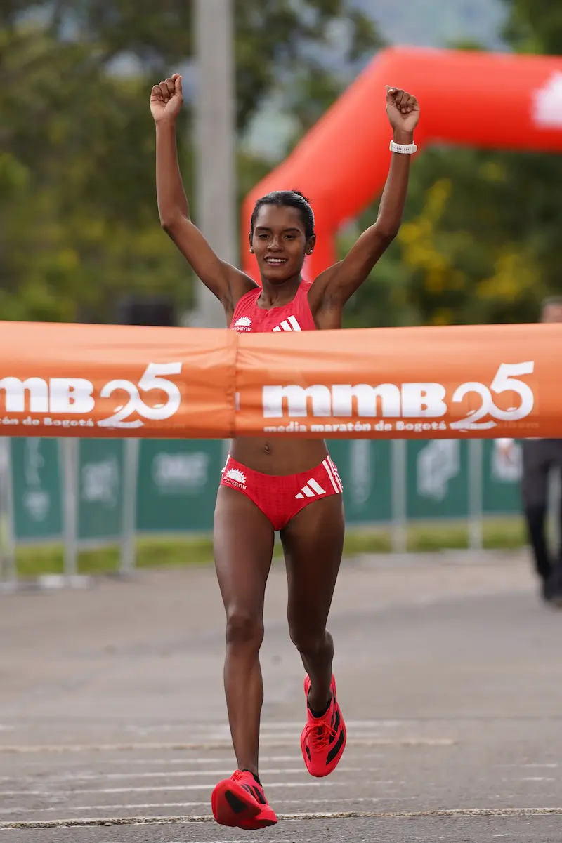 Mujer cruzando meta de su primera media maratón con orgullo y satisfacción