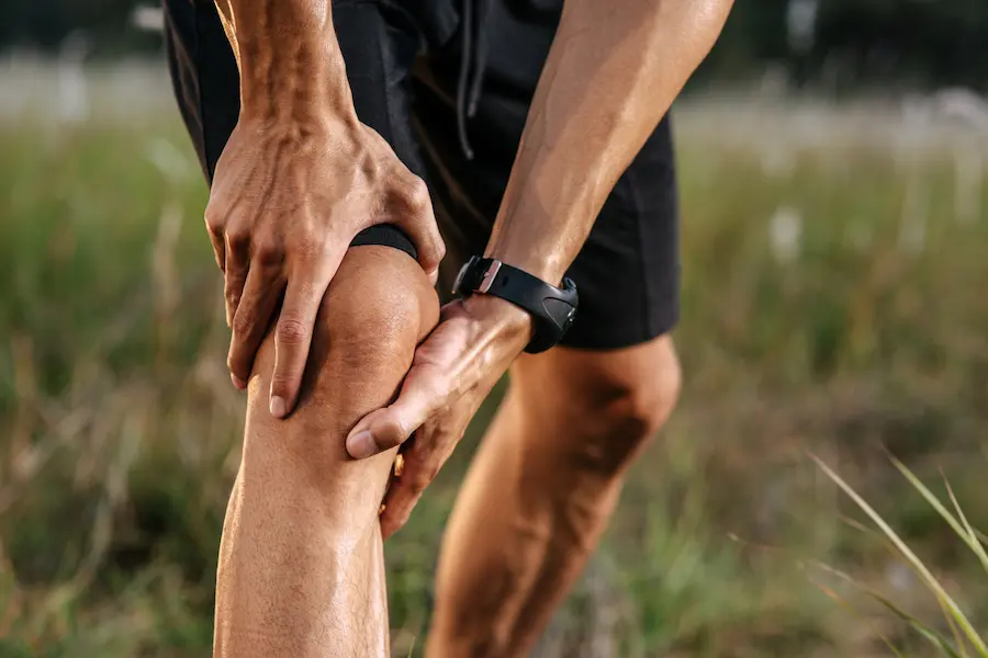 Corredor sujetando su rodilla por dolor, reflejo de lesiones comunes al correr