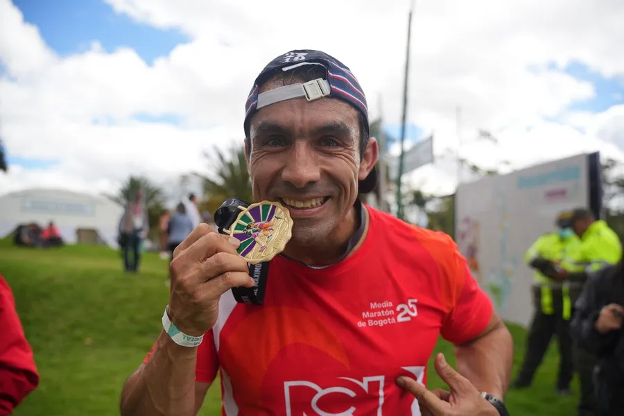 Corredor de 50 años cruzando meta con sonrisa de satisfacción personal