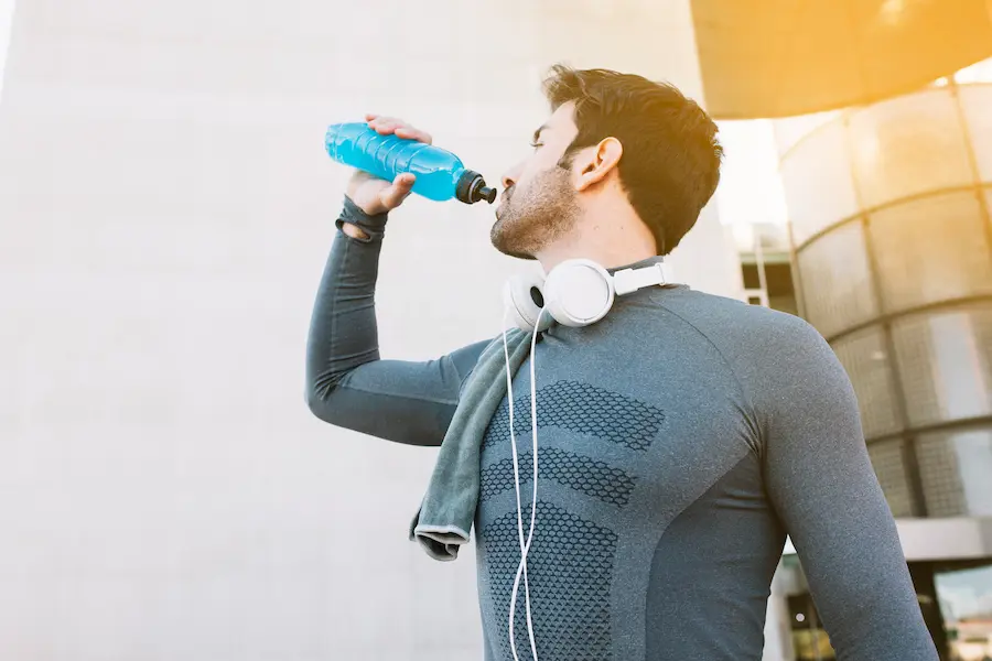 Atleta hidratándose estratégicamente para minimizar deriva cardíaca durante media maratón