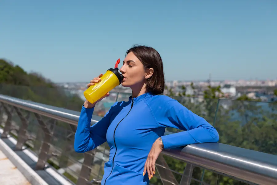 Corredora hidratandose con agua de panela en su entrenamiento de running matutino