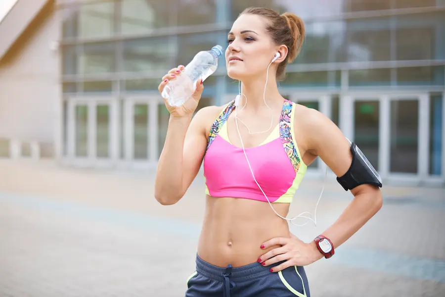 Corredora hidratándose correctamente con agua